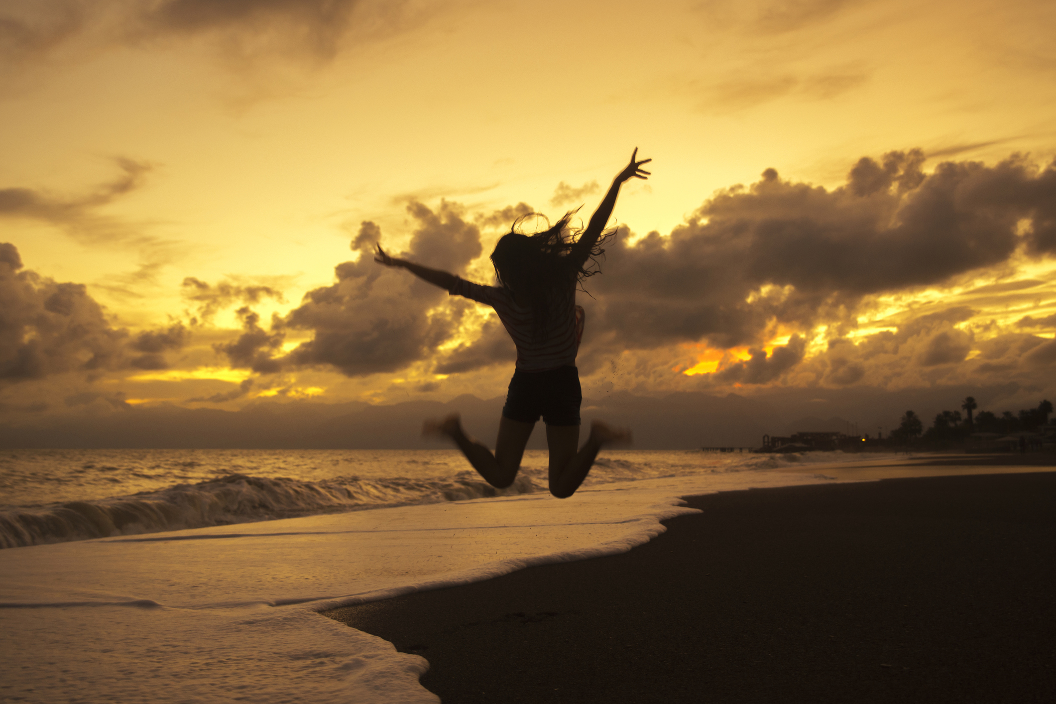 silhouette-woman-jumping-beach-sunset