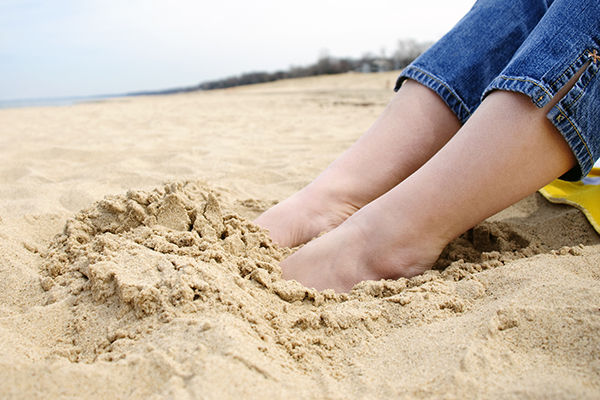 Female Feet Buried in Sand at the Beach