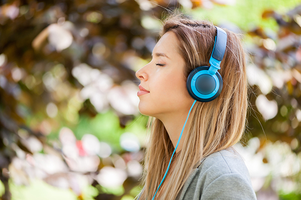close up of young woman listening music at the park