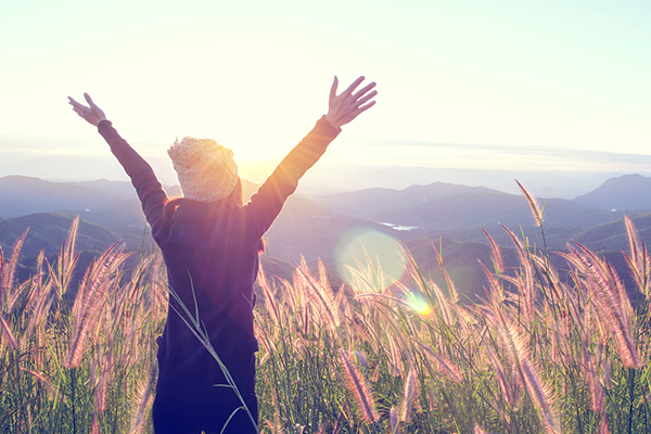 happy woman enjoying nature on meadow on top of mountain with sunrise outdoor freedom