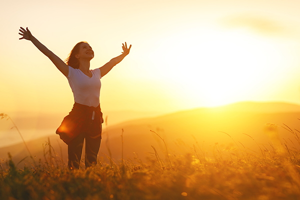 Happy woman on sunset in nature with open hands