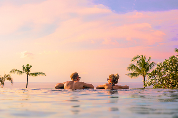 Couple looking at beautiful sunset in infinity pool