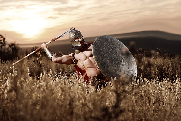 Strong Spartan warrior in battle dress with a shield and a spear