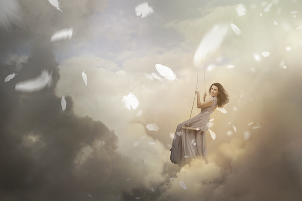 woman-swinging-in-sky-with-falling-feathers