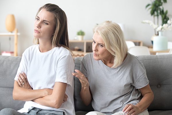 Aged mom lecturing adult daughter sitting at home together